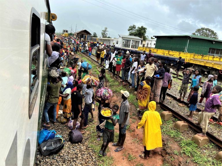 At every station (and there are many) the train is mobbed by vendors and potential passengers. Taking the train from Cuamba to Nampula. Public transport, train travel in Mozambique